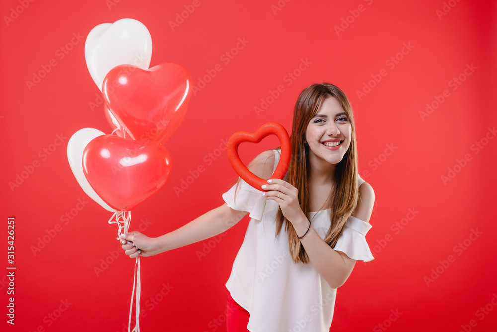 beautiful woman with red heart shape and colorful balloons in the air isolated on red background beautiful woman with red heart shape and colorful balloons in the air isolated on red background
