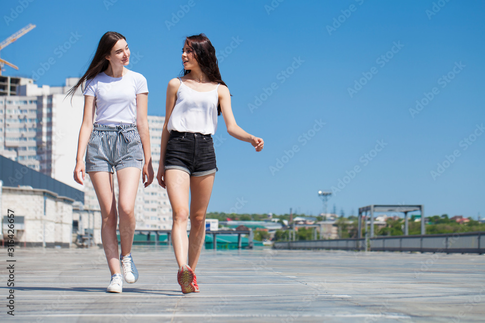 Two girlfriends walking on summer street, outdoors