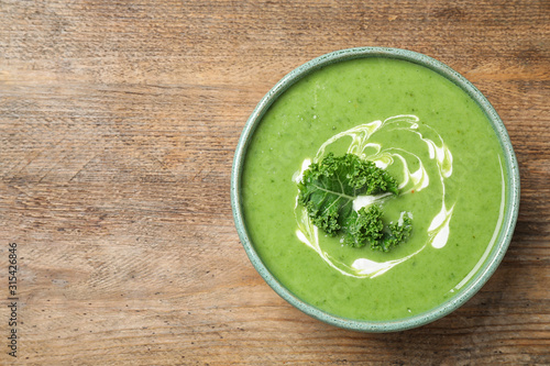 Tasty kale soup on wooden table, top view. Space for text