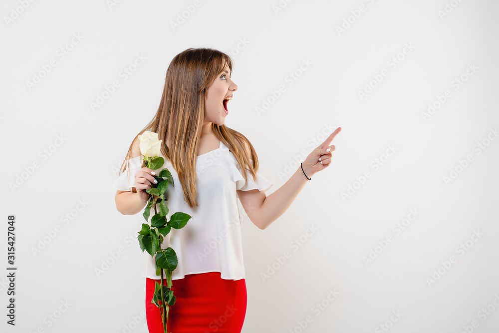 woman with rose pointing finger at copy space wearing red skirt and blouse isolated over white woman with rose pointing finger at copy space wearing red skirt and blouse isolated over white