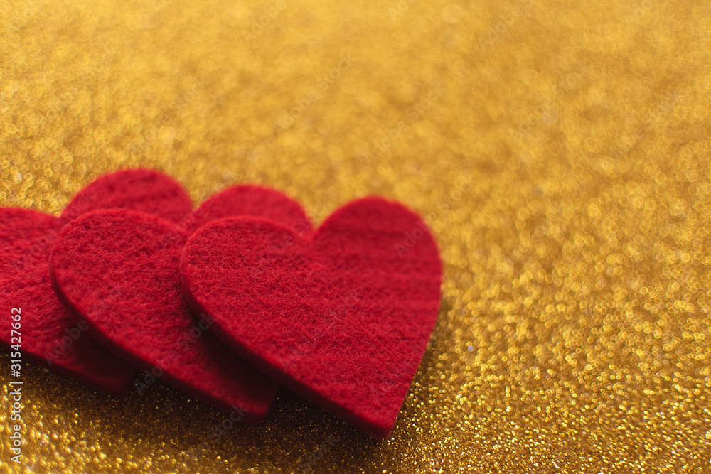 Obraz premium Red felt hearts on golden shiny background. Valentine's Day