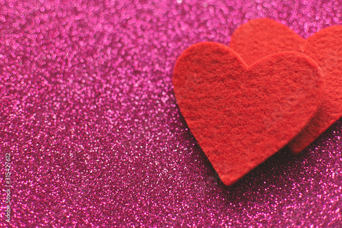 Red felt hearts on a pink shiny background. Valentine's Day