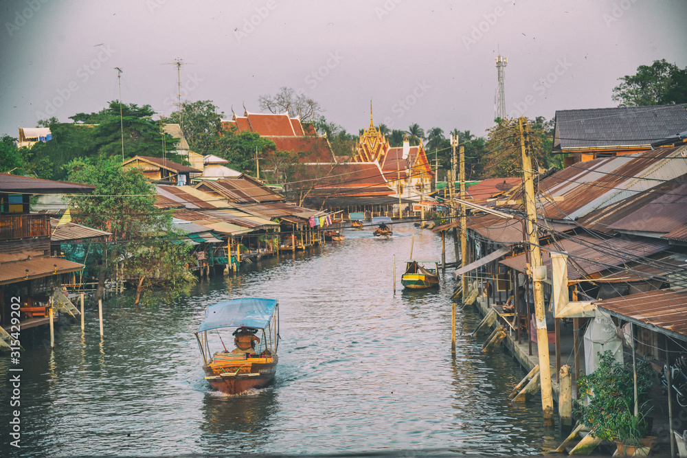 Wooden boats busy ferrying people at Amphawa floating market in Bangkok. A traditional popular method of buying and selling still practiced in Amphawa canals of Thailand