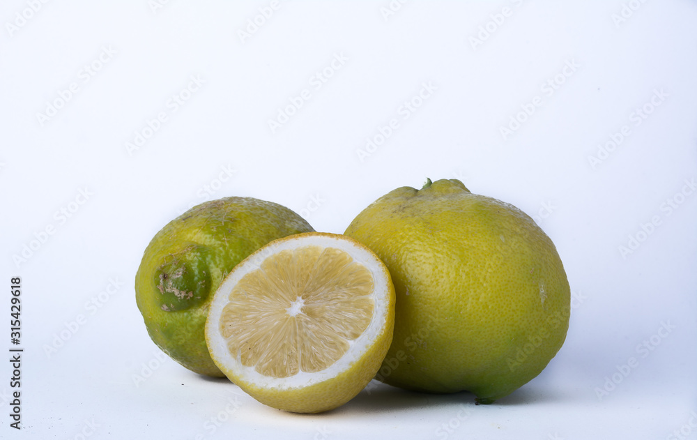 Detail of a cut lemon accompanied by two other yellow lemons on a white background. Horizontal format. Detail of a cut lemon accompanied by two other yellow lemons on a white background. Horizontal format.