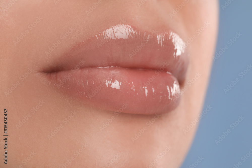Young woman with beautiful full lips on light blue background, closeup Young woman with beautiful full lips on light blue background, closeup