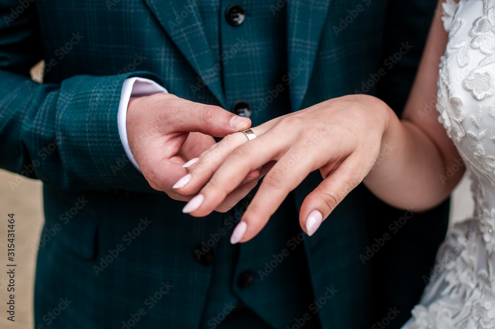 Groom holding hand of the bride with gold wedding ring