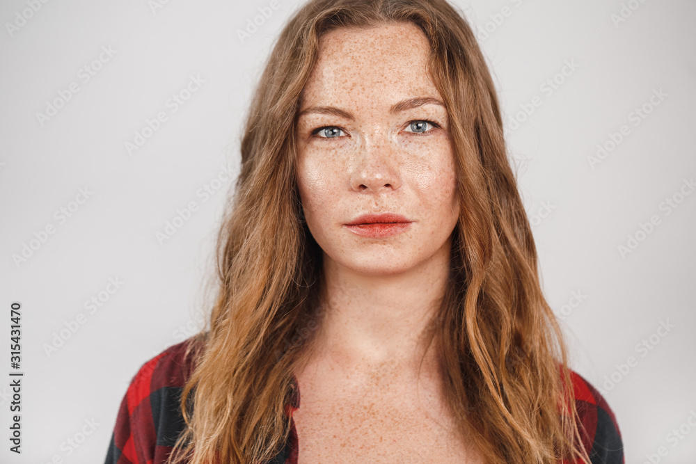 Freestyle. Young woman with freckles standing isolated on grey confident close-up Freestyle. Young woman with freckles standing isolated on grey confident close-up
