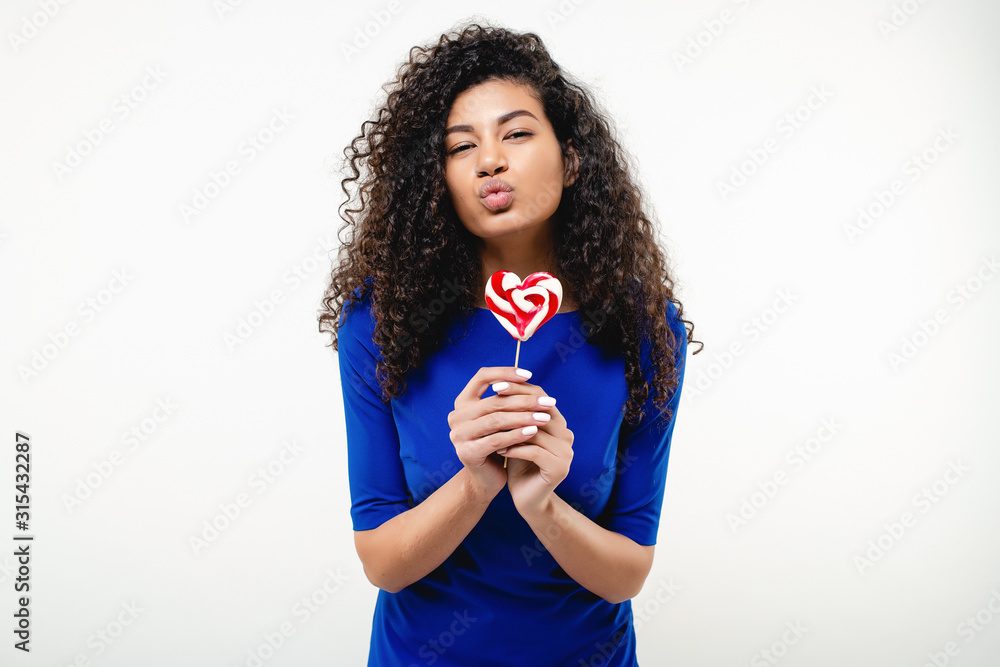 happy black woman with heart shaped lollypop candy isolated over white background happy black woman with heart shaped lollypop candy isolated over white background