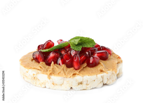 Puffed rice cake with peanut butter, pomegranate seeds and mint isolated on white