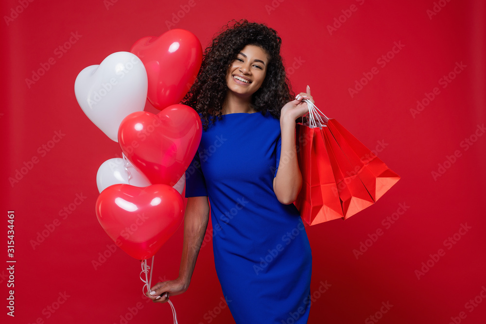 black woman with heart shaped colorful balloons and shopping bags on red background black woman with heart shaped colorful balloons and shopping bags on red background