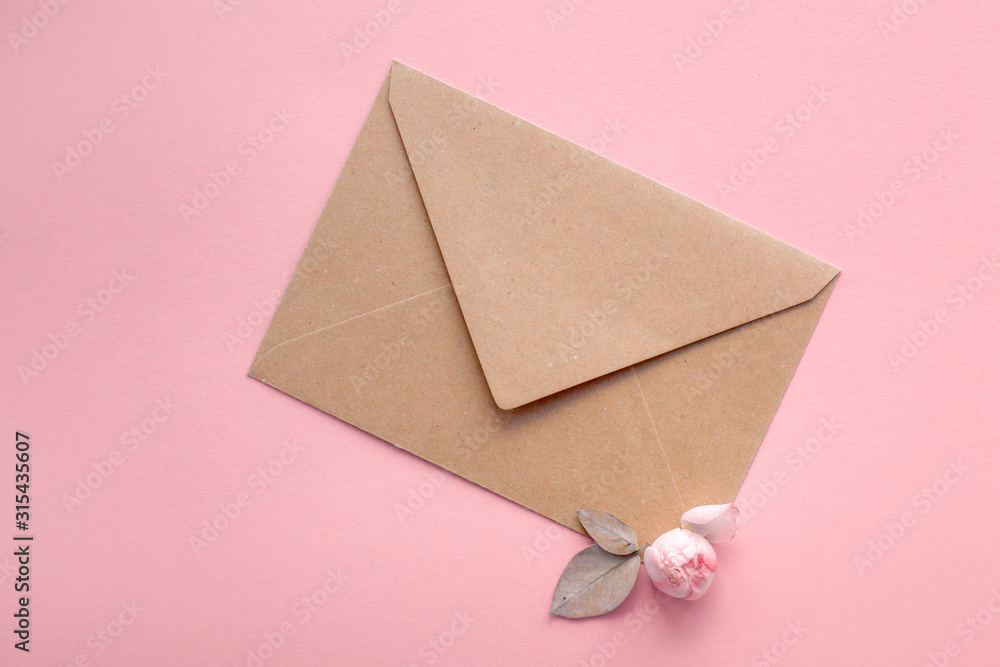 Pink roses on an envelope from kraft paper on a pale pink background. Message for Valentine's Day, Women's Day, Wedding. Flat lay, top view Pink roses on an envelope from kraft paper on a pale pink background. Message for Valentine's Day, Women's Day, Wedding. Flat lay, top view