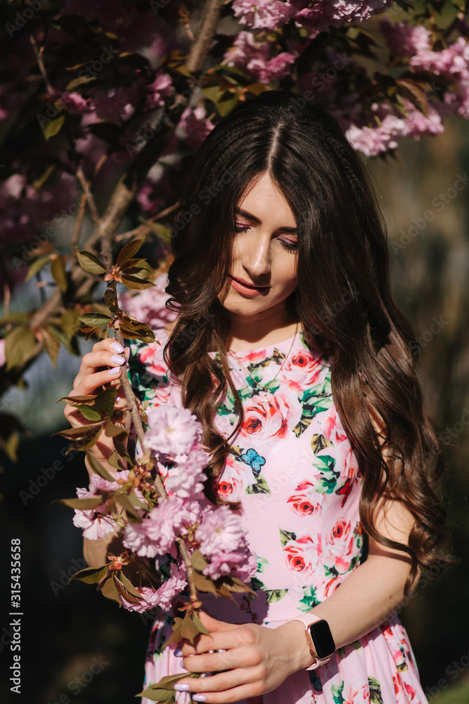 Fototapeta premium Close up of beautiful woman near the pink tree with makeup close her eyes