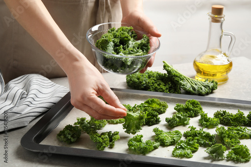 Photos Woman preparing kale chips at table, closeup