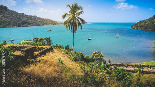 A beautiful panoramic view of the Pirate Bay of Portobelo in Panama with its historical Forts Ruins & Cannons on a Hill with some Sailboats anchored in the Blue Lagoon at the Caribbean Coast.