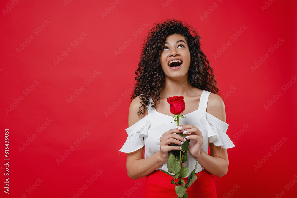 happy smiling black woman with red rose in hand isolated over red happy smiling black woman with red rose in hand isolated over red