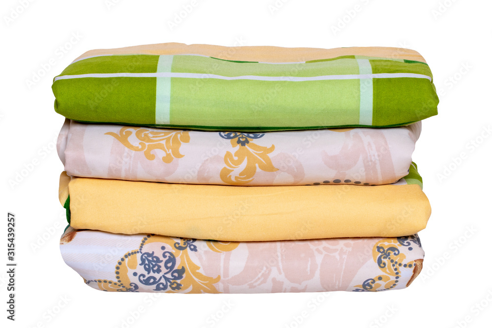Bed linen isolated. Close-up of a stack or pile of colorful folded bed linen or duvet covers isolated on a white background. Macro of washed and ironed fabric, useful for laundry service or textile re