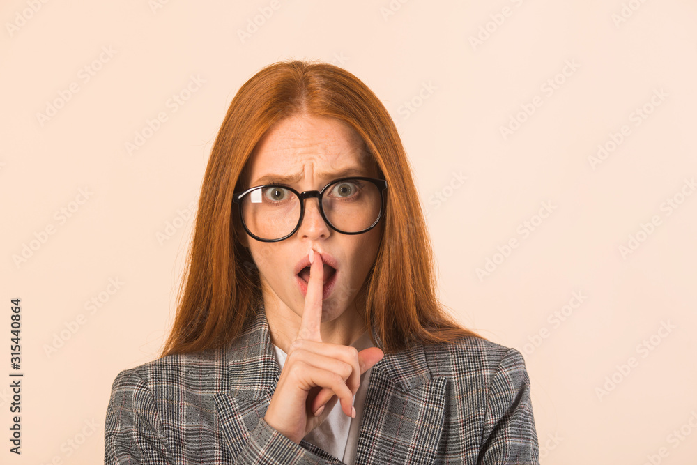 beautiful young woman with red hair in a jacket on a beige background