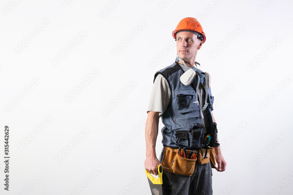Builder with a saw. In work clothes and a helmet. On a light gray background. Builder with a saw. In work clothes and a helmet. On a light gray background.