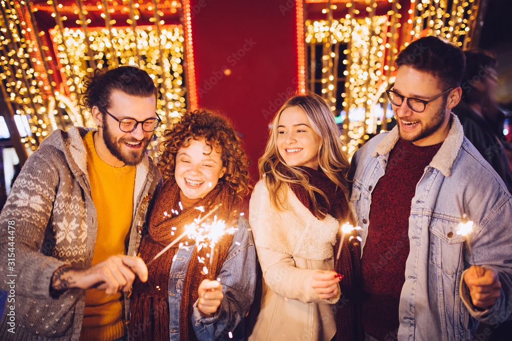 Group of happy friends celebrating New Year with sparklers. New year party. Group of happy friends celebrating New Year with sparklers. New year party.