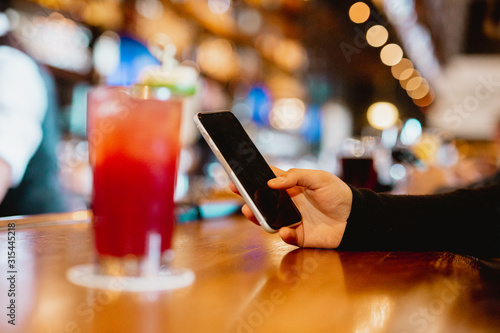 Woman enjoying drink at bar on her phone
