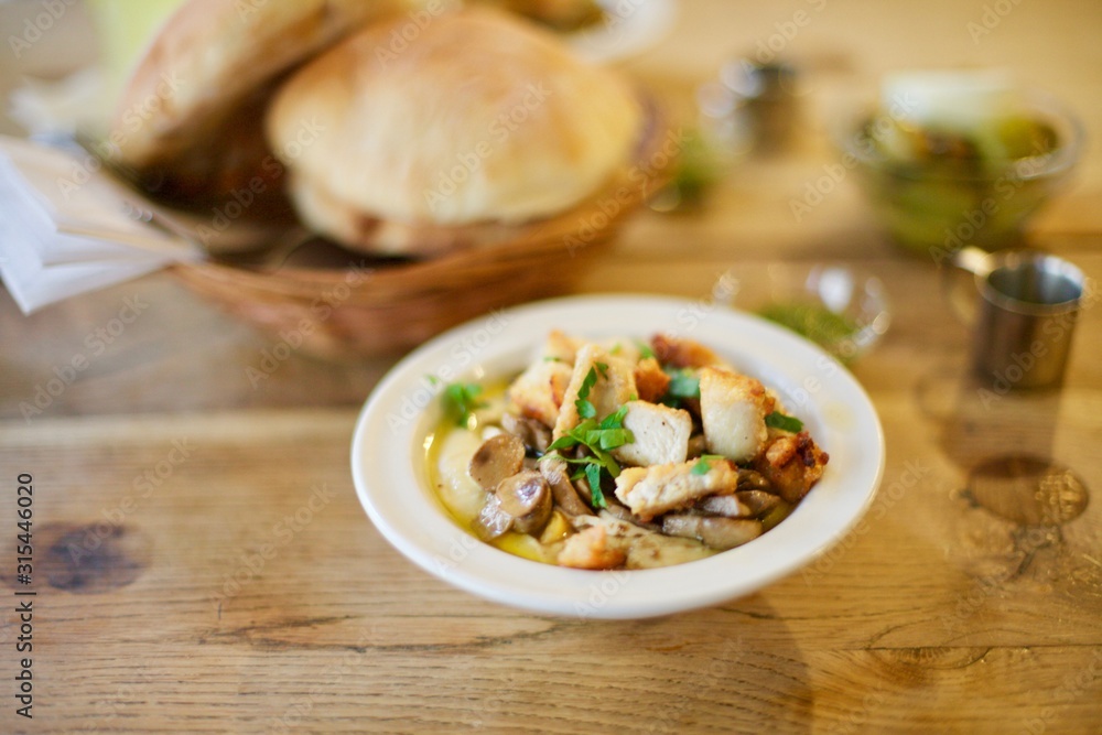 A bowl of chicken and hummus served with flat bread A bowl of chicken and hummus served with flat bread
