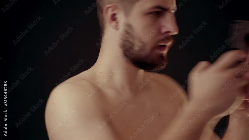 Close-up portrait of shirtless surprised man rejoicing as he is looking at his mobile phone Close-up portrait of shirtless surprised man rejoicing as he is looking at his mobile phone