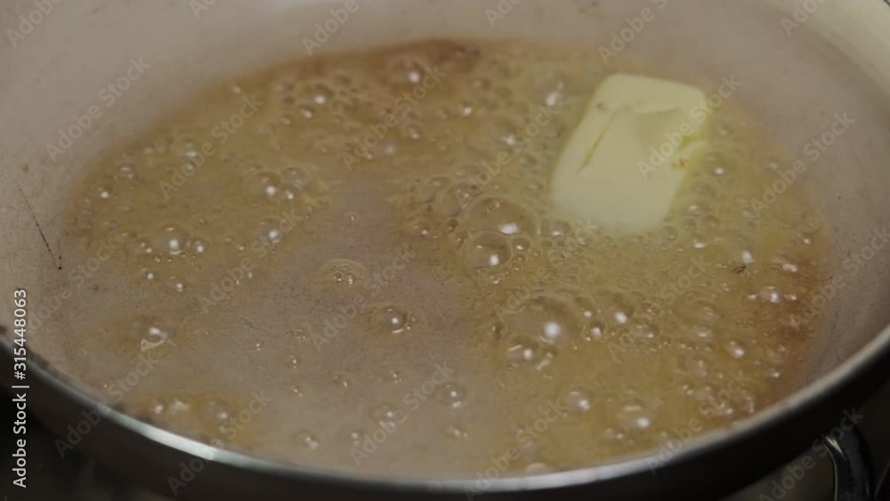 Top view of Butter slowly melts in a hot frying pan on a stove Top view of Butter slowly melts in a hot frying pan on a stove