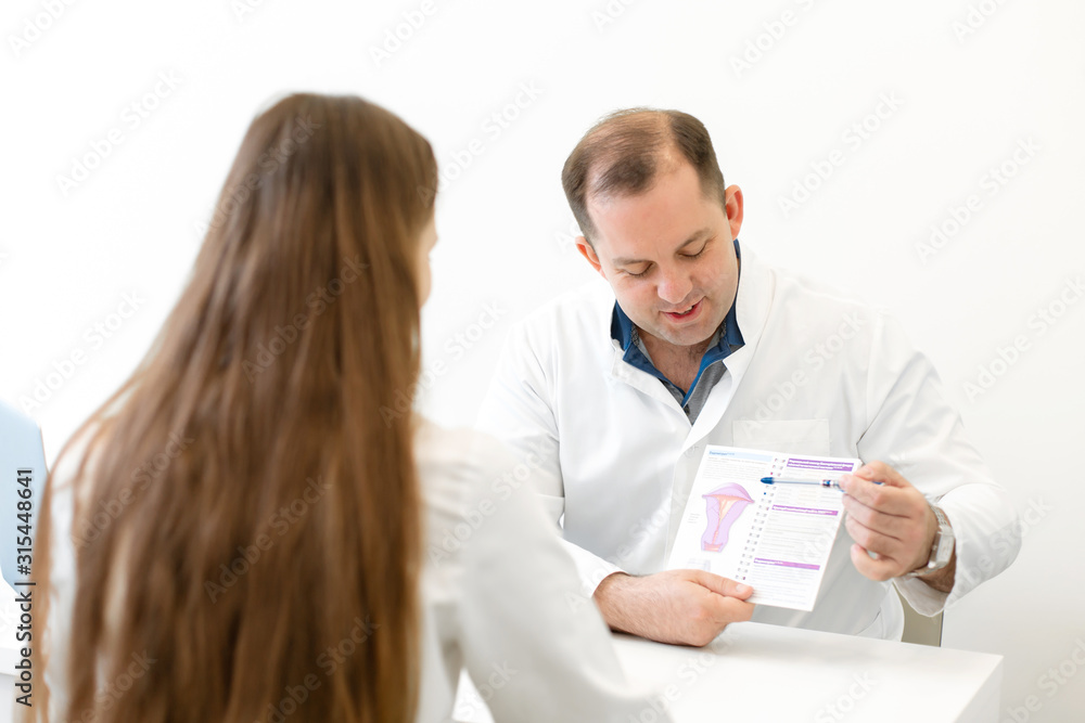A male gynecologist consults a young girl about the menstrual cycle, showing the menstrual calendar. Professional medical consultation A male gynecologist consults a young girl about the menstrual cycle, showing the menstrual calendar. Professional medical consultation