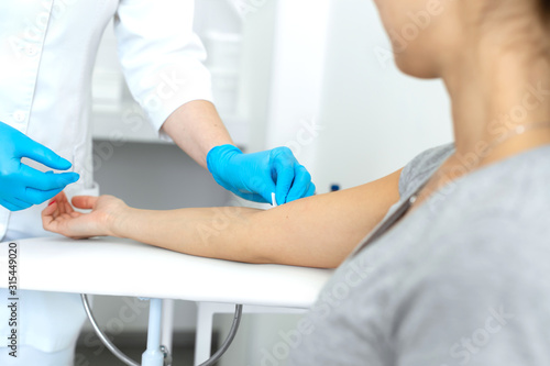 A nurse wipes a patient hand with a cotton pad soaked in an antiseptic. Blood sampling procedure