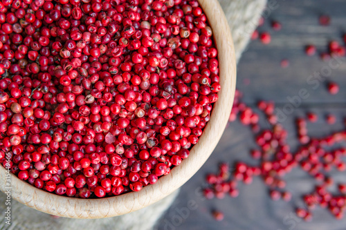 Photos Close up view of pink peppercorn (Brazil Pepper or Schinus terebinthifolius) in wooden bowl, dark rustic background