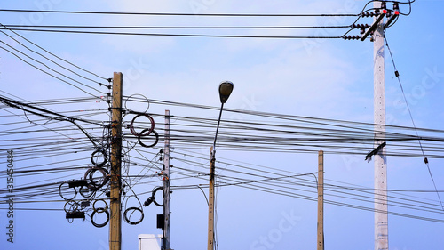 Obraz na płótnie Messy electrical cable lines and wires on power pols against cloud and blue sky background