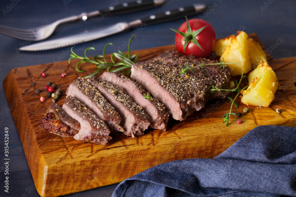 Grilled fillet beef steak with potatoes on serving board Grilled fillet beef steak with potatoes on serving board