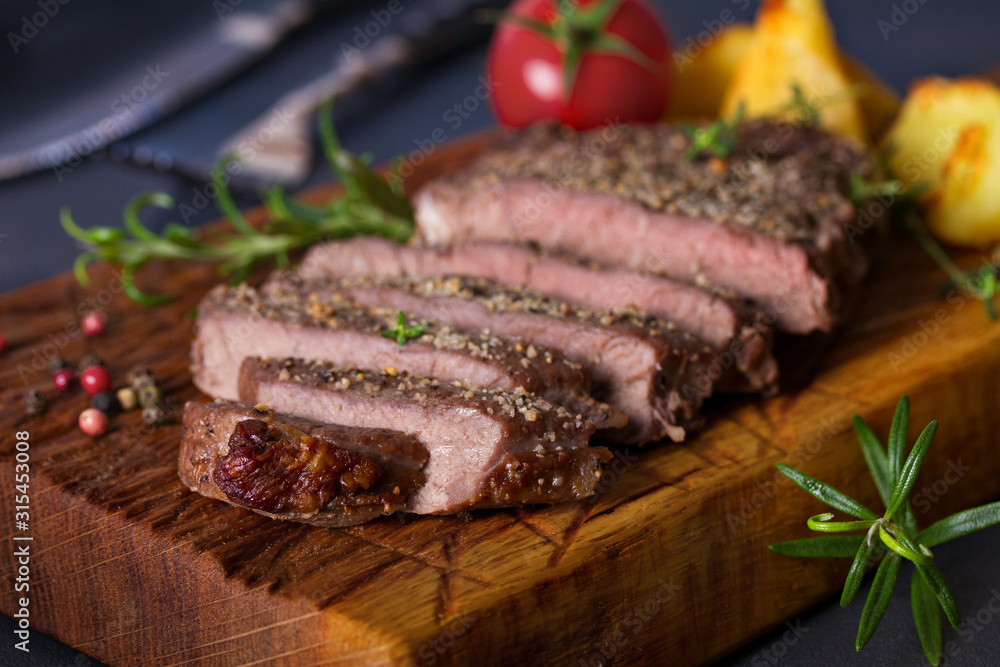 Grilled fillet beef steak with potatoes on serving board