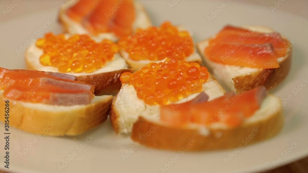 A plate with sandwiches with red fish and red caviar rotates in a circle. A plate with sandwiches with red fish and red caviar rotates in a circle.