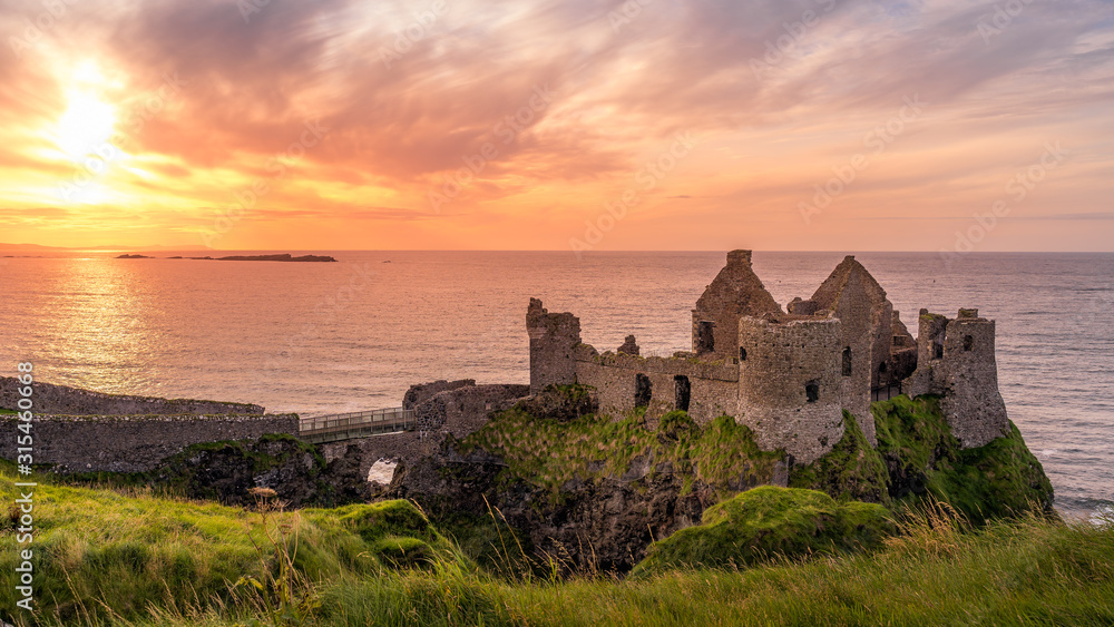 Ruined medieval Dunluce Castle on the cliff at amazing sunset, Wild Atlantic Way, Bushmills, County Antrim, Northern Ireland. Filming location of popular TV show, Game of Thrones, Castle Greyjoy