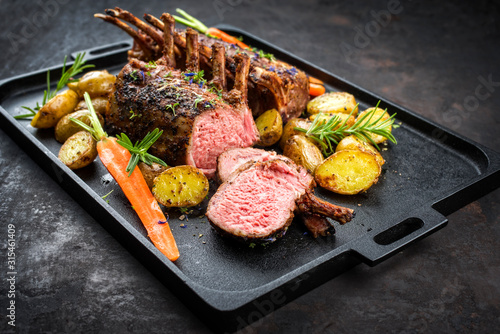 Fotografia, Obraz Barbecue rack of lamb with carrot and potatoes offered as closeup on a modern de
