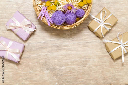 Flat lay of flowers, petals, leaves and gifts. Holiday yellow, purple and white decor on the wooden table. 
