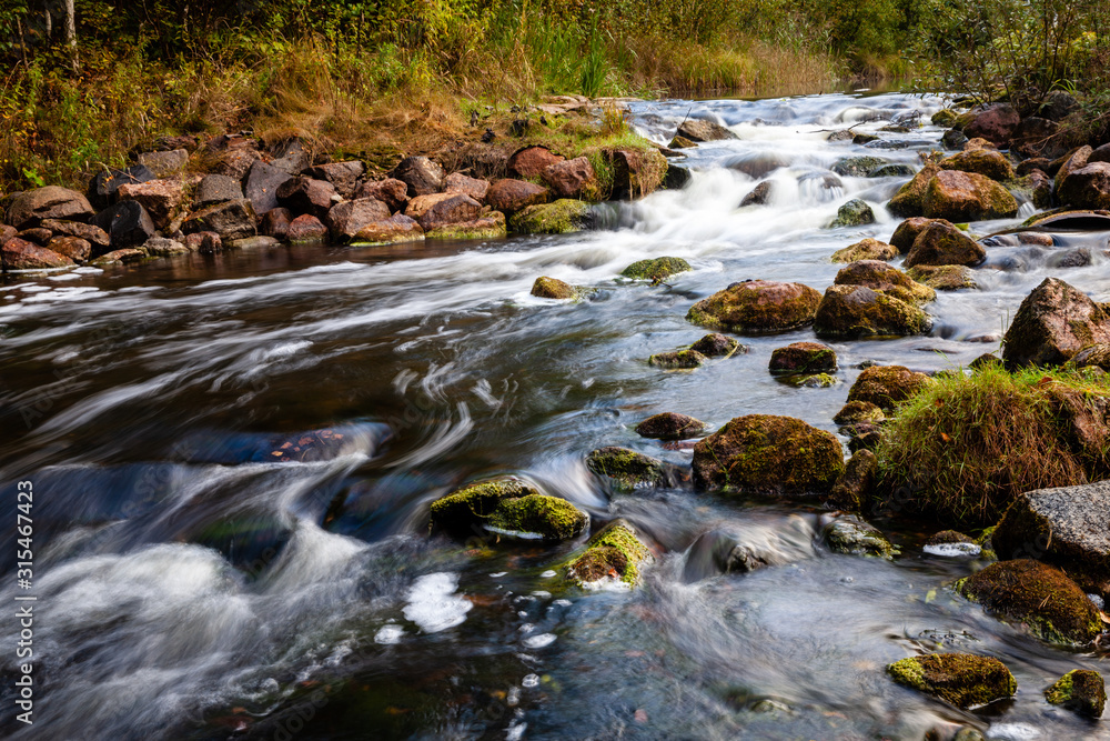 Rapids, wild river near Endla bog, Estonia. Raging water and mossy rocks at bank sides...