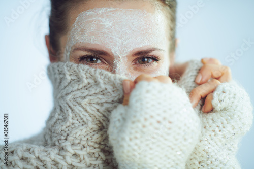 elegant woman with white facial mask hiding behind clothes photo