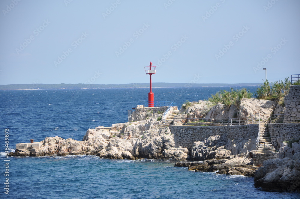 Red lighthouse on Croatian rocky coast. Mediterran background.