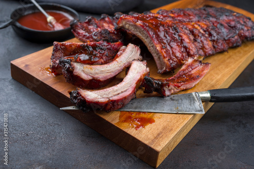 Barbecue Schweine Spare Ribs  St Louis cut mit scharfer Honig Chili Marinade als closeup auf einem Modern Design Holz Board photo