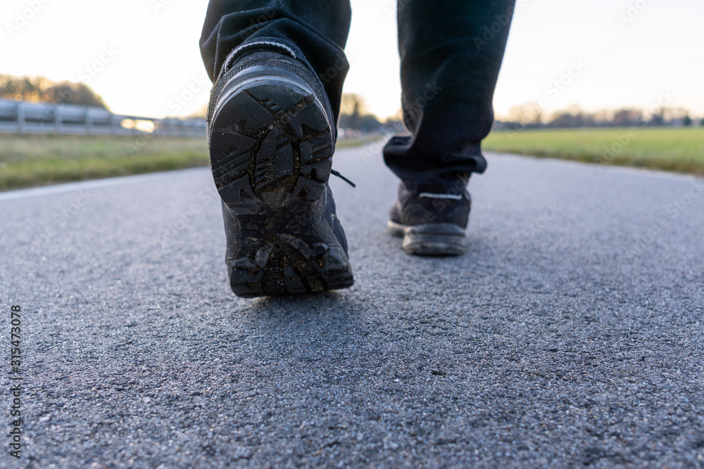 The close up shot of walking shoes on the road, selected focus on the left shoe The close up shot of walking shoes on the road, selected focus on the left shoe