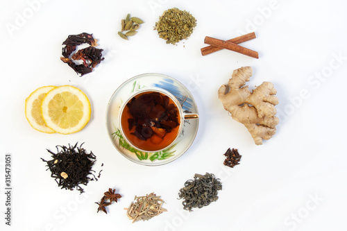 A cup with tea surrounded by different types of teas and warming, healing spices 