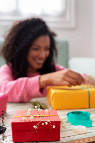 Latin woman wrapping handmade craft gifts on the table at home