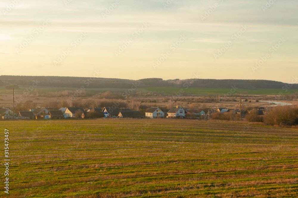 Ancient houses in country side, sunset in field and russian village