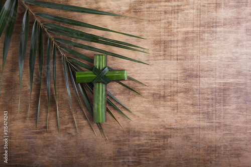 Palm sunday concept: Cross shape of palm branch on an antique wooden background