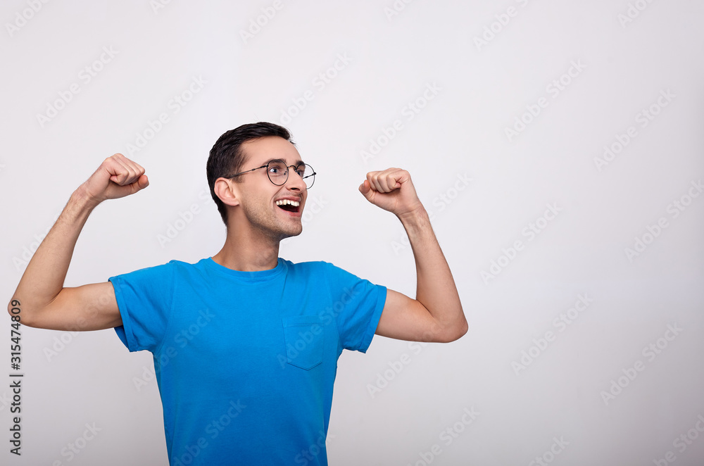 A young man in glasses and a blue T-shirt celebrates the victory. A young man in glasses and a blue T-shirt celebrates the victory.