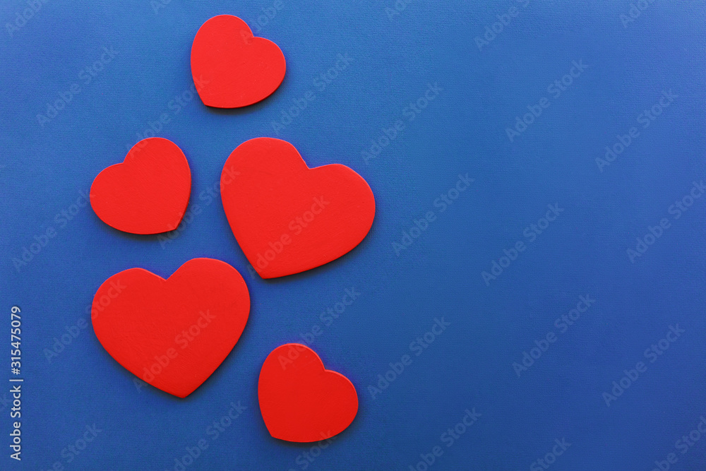 Many wooden red hearts on blue background, Valentine's Day concept, close-up. Place for text