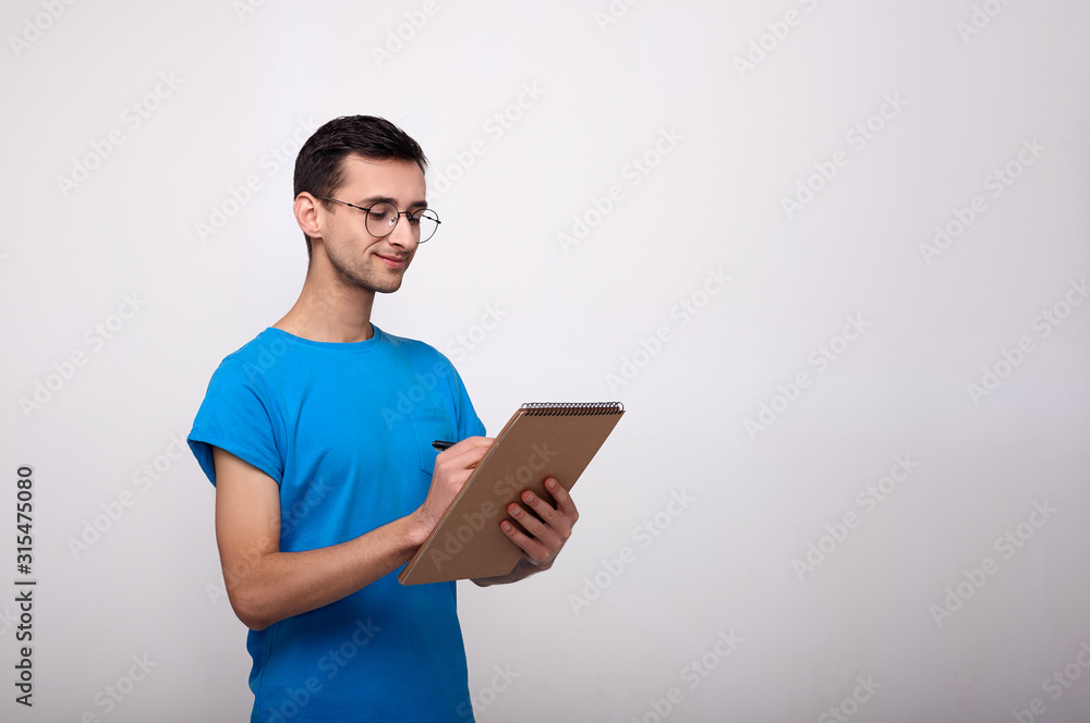 A handsome guy writes in a brown notebook. A handsome guy writes in a brown notebook.
