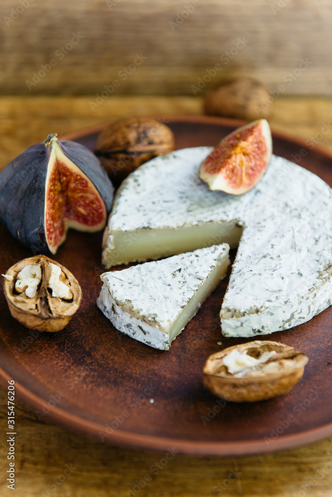 Handmade brie cheese in herbs and figs